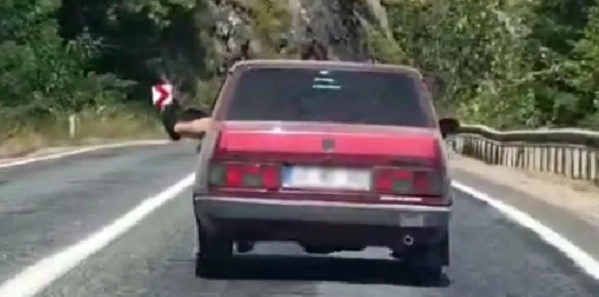 Ayaklarını camdan sarkıtarak trafiği tehlikeye attı